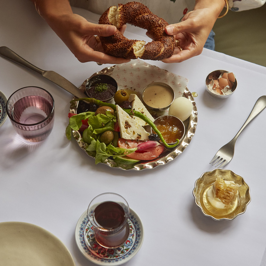 Hands tearing bread and a plate of food at Leydi restaurant, Hyde London